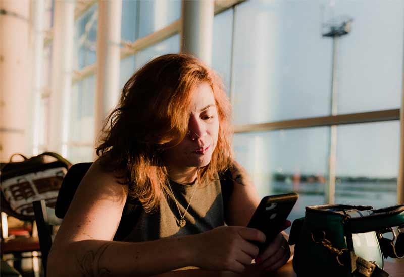 a lady sits in airport making secure purchase on her phone